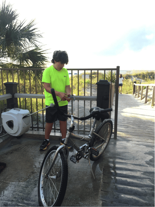 Chris Cox washing his bike after riding on the beach with his family