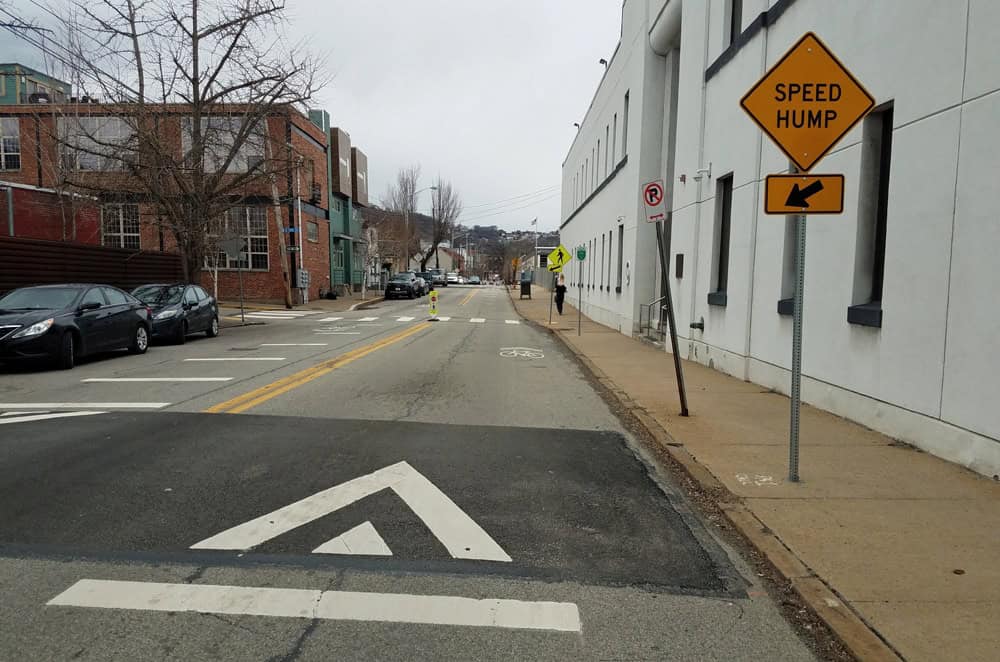 Image shows a speed hump and relevant signage and road markings used to calm traffic on Muriel St in the South Side, making it safer for people on bikes or on sidewalks