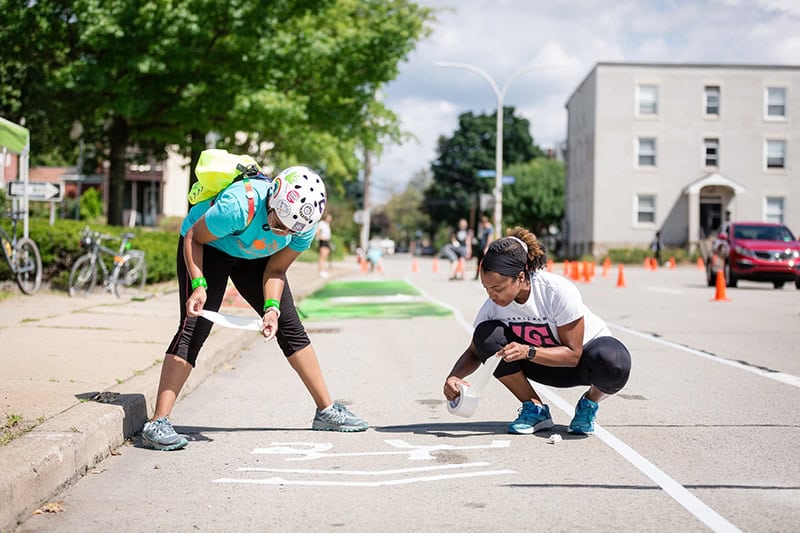 Two volunteers setting up the "pop-up" Parking Protected bike lane demonstration in East Liberty