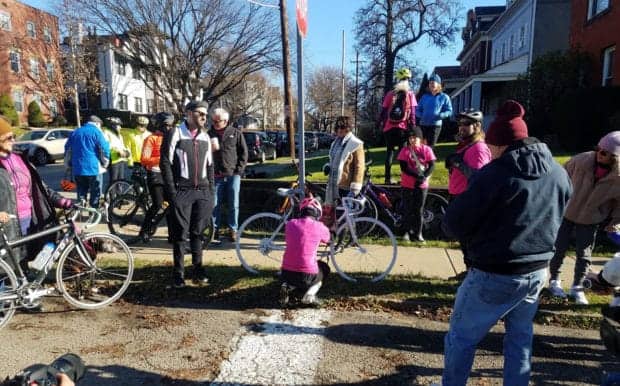 Picture of people gathered around the white ghost bike of Will Theisen near Stanton Ave.