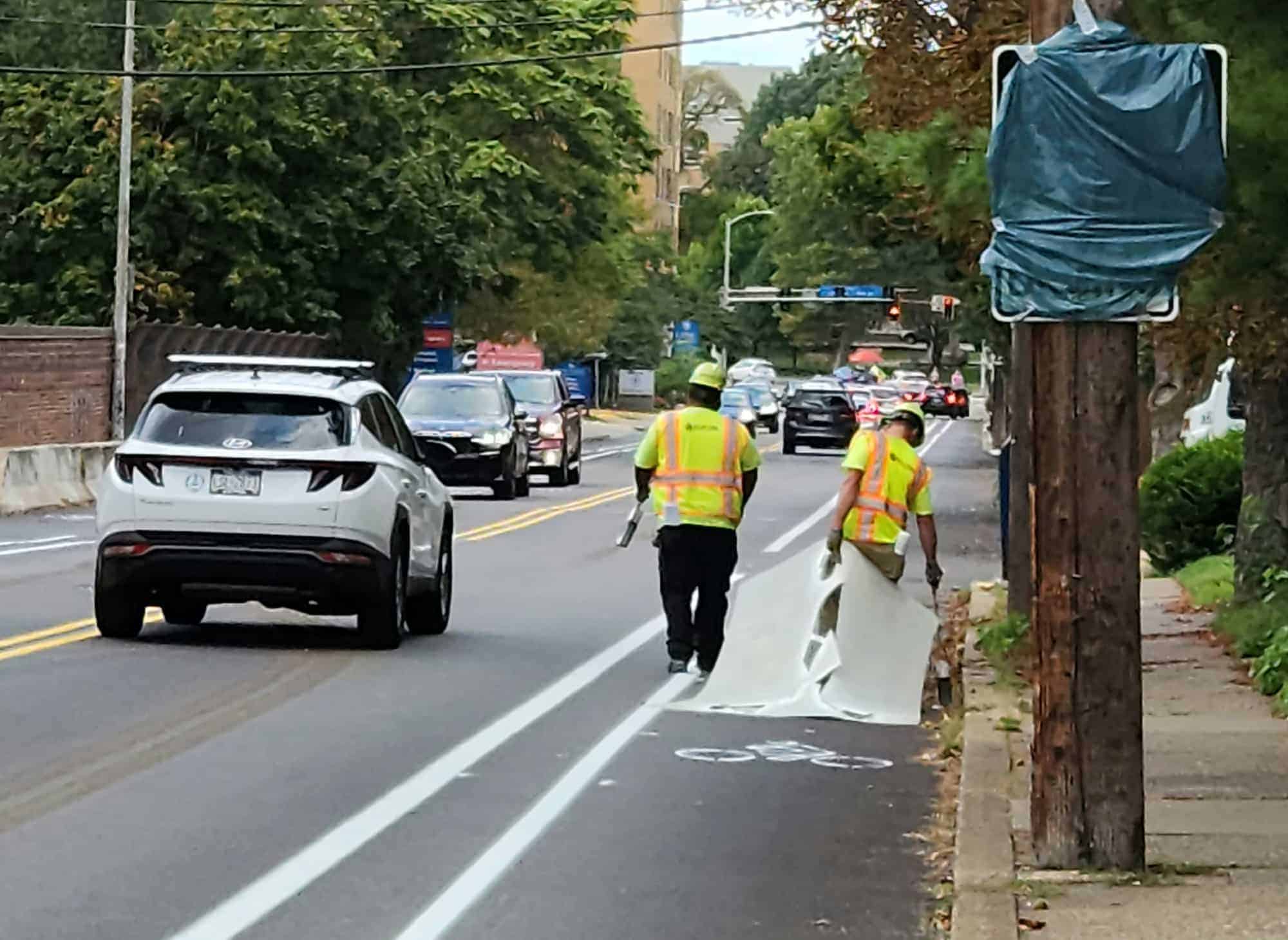 Workers holding a stencil as they build the S Aiken Bike Lanes