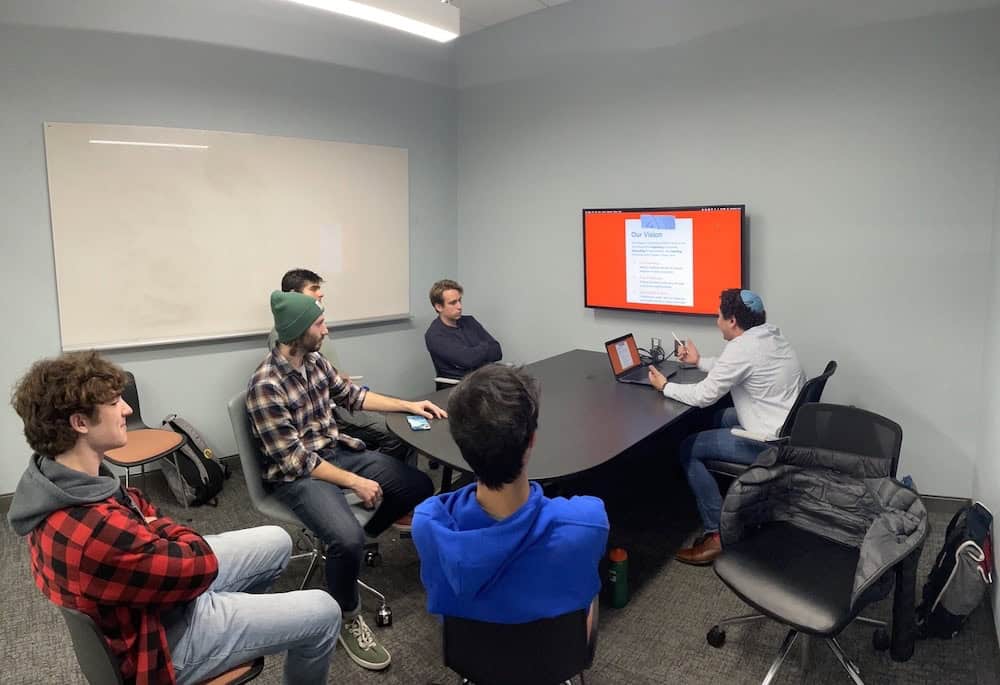 Image shows students sitting around a table talking