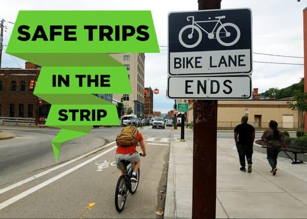 Text "Safe Trips In The Strip" on a green ribbon over a picture of someone biking by a sign that says "bike lane ends"