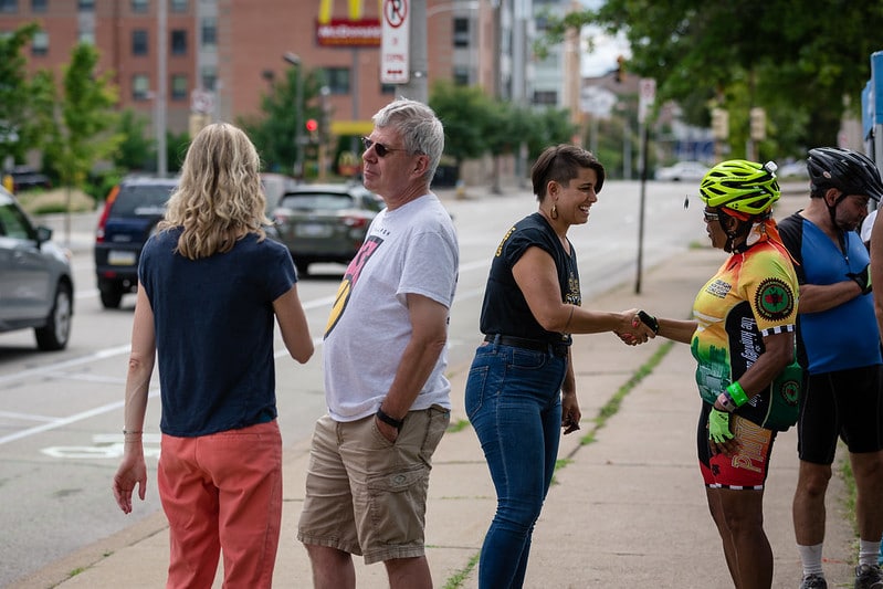 Picture of a cyclist wearing a helmet talking with a State Representative in front of a bike lane.