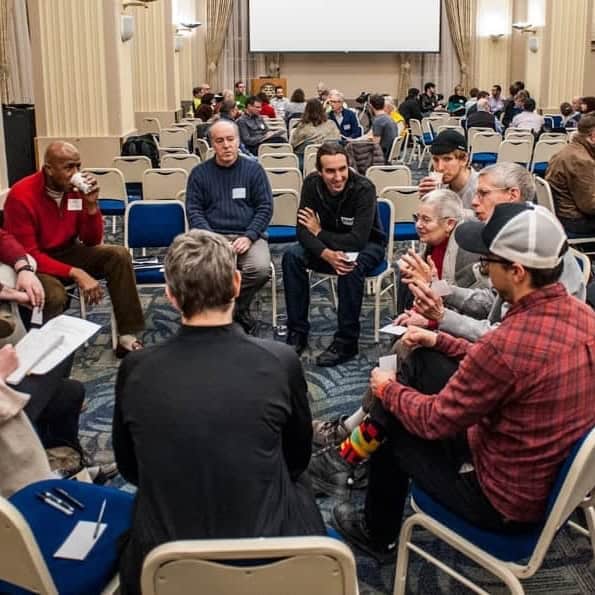 People seated in a circle talking with one another.