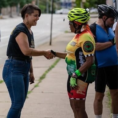 Picture of a person wearing biking gear shaking hands with Sara Innamorato.