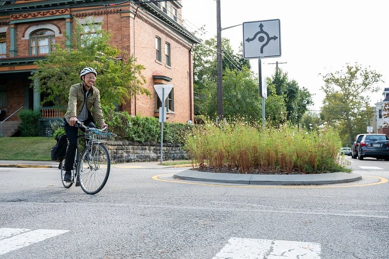 Picture of a person riding their bike around a traffic circle.