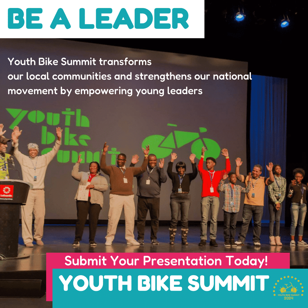 Adult and youth bike summit representatives stand on a stage celebrating with their arms outstretched. 