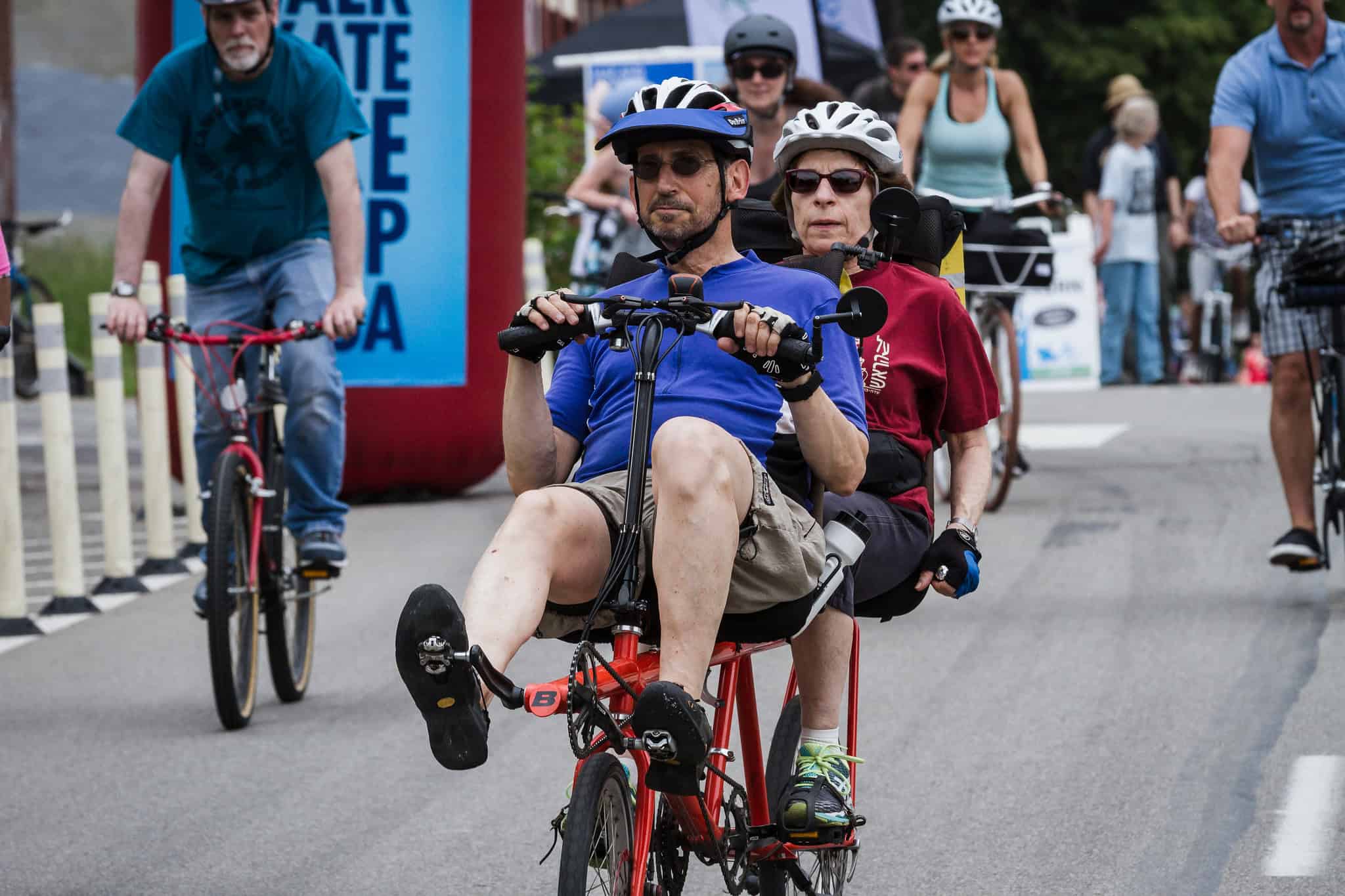 A picture of two older adults riding a tandem recumbent bicycle.