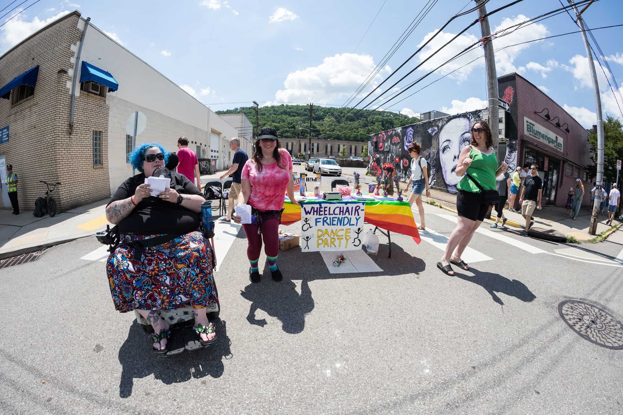 A picture of a "wheelchair friendly dance party" at Open Streets PGH. People are dancing including a person in an electric wheelchair.