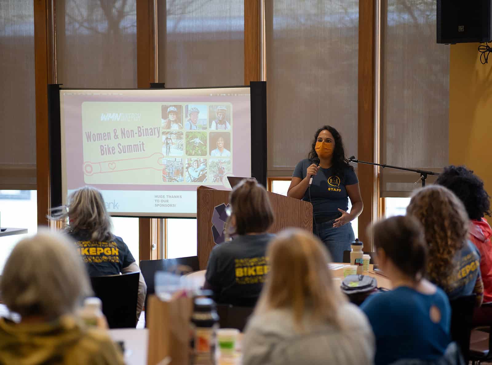 Picture of a woman wearing a mask speaking to an audience of women and non binary people at BikePGH's Women & Non-Binary Bike Summit.