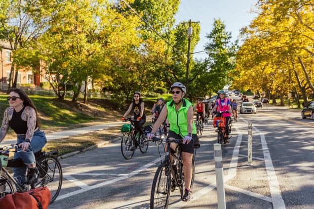 A group of women, trans and nonbinary cyclist enjoy a group bike ride along a bike lane.