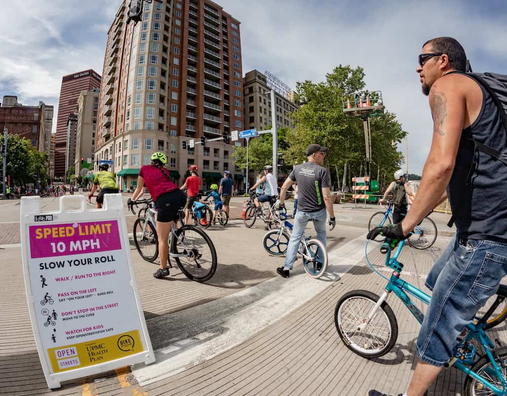 Folks riding bikes in Downtown Pittsburgh at OpenStreetsPGH with a Speed Limit 10 mph sign posted