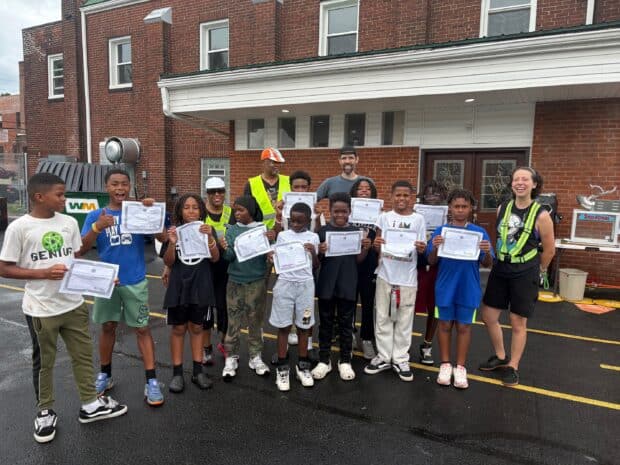 Ten students aged between ten and fifteen pose with their safe cycling awards with their instructors, Neil, Sarah, Robin, and Ted. 