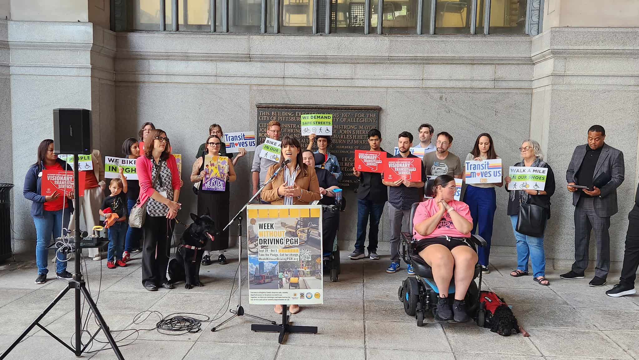 Image of Allegheny County Executive Sara Innamorato speaking with a crowd holding signs behind her