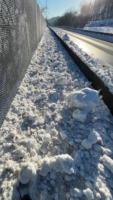 Tons of chunky, icy snow completely covering a pedestrian walkway fully across a bridge