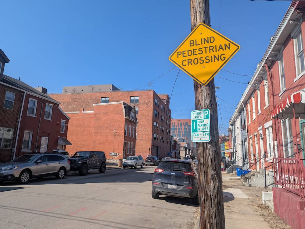 A photo of a "Blind pedestrian crossing" yellow street sign located in Pittsburgh's Uptown area, on Locust Street.