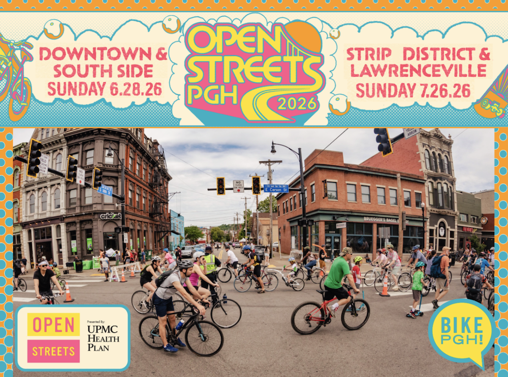 20 to 30 people of all ages walking and biking on E Carson St in Pittsburgh's South side