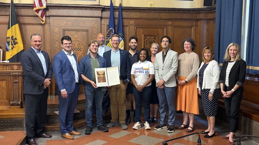 A 12-person group photo at the City-County Building chambers with City Councilpeople and representatives from Week Without Driving PGH, smiling and holding up the City Proclamation 