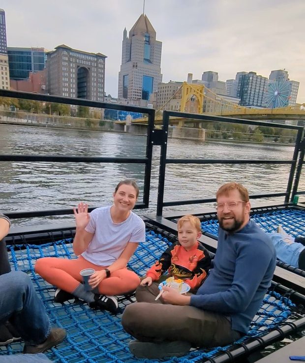 Emilee, her 3 year old son, and  her husband wave to the camera while lounging at the Shore Thing.