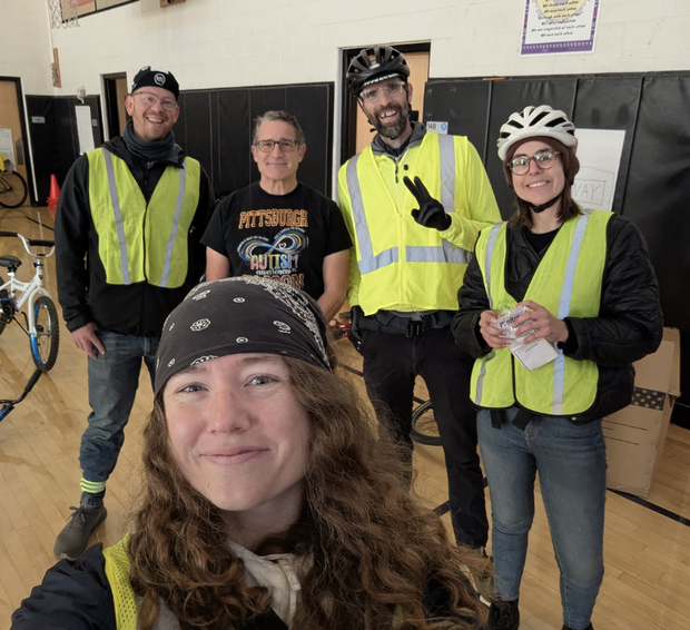 A group photo of BikePGH staff in neon "bike bus" vests with the gym teacher from Faison. 